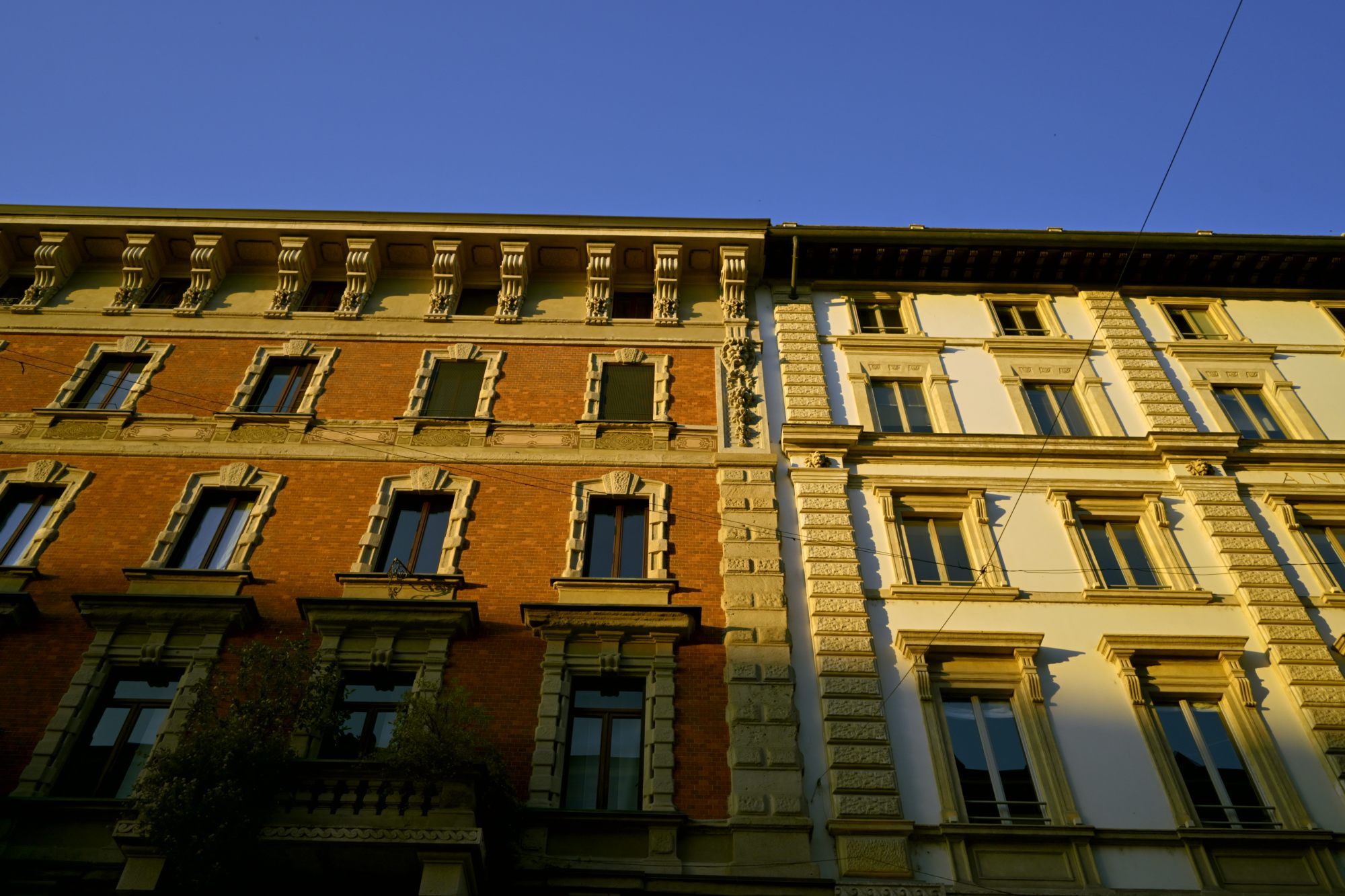 Sunlit Milanese facades seen looking upward.