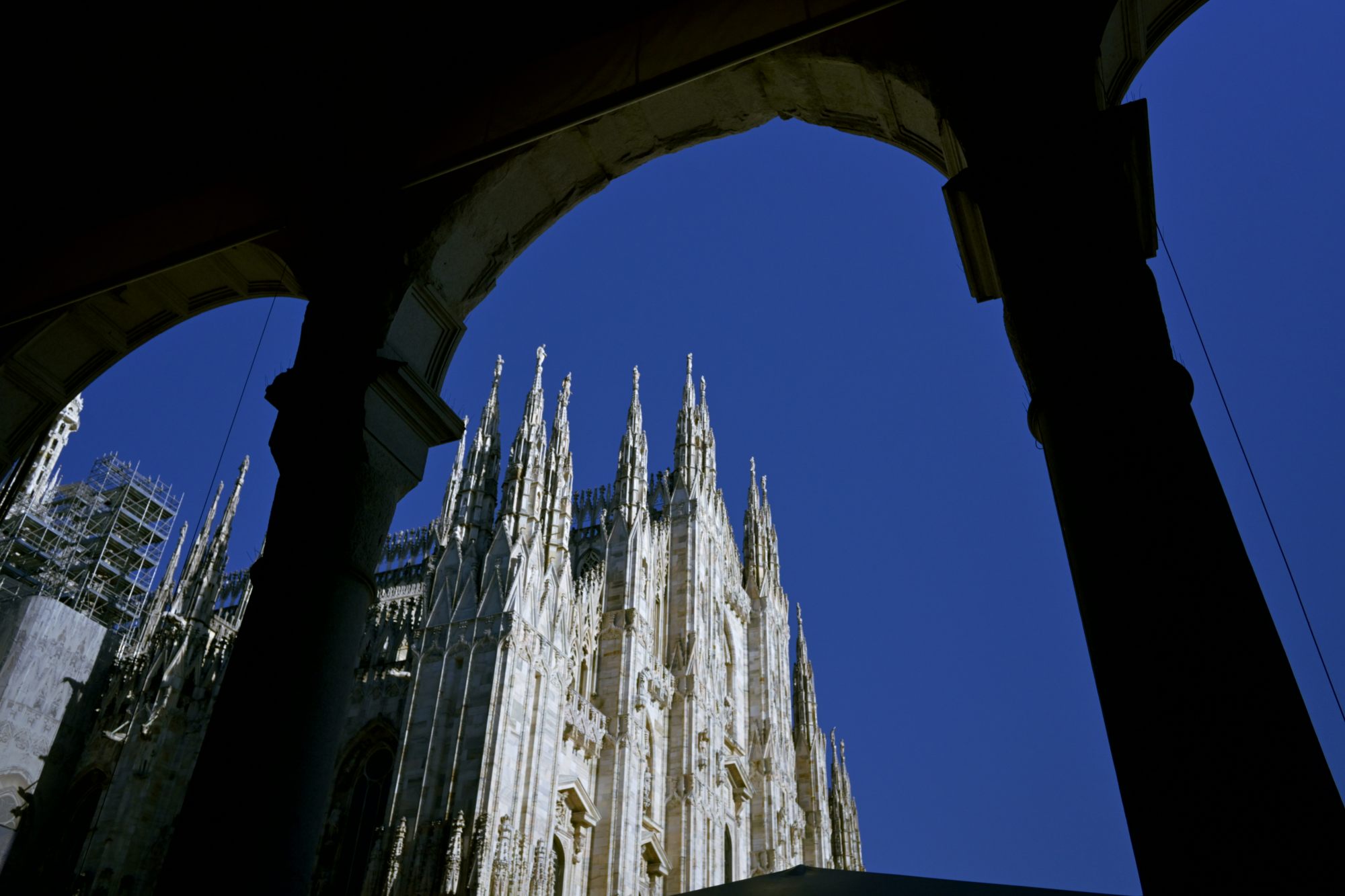 The spires of the Duomo framed through an arch.