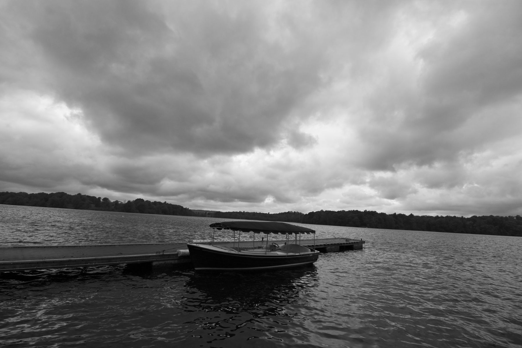 A boat on a still lake under grey cloud.