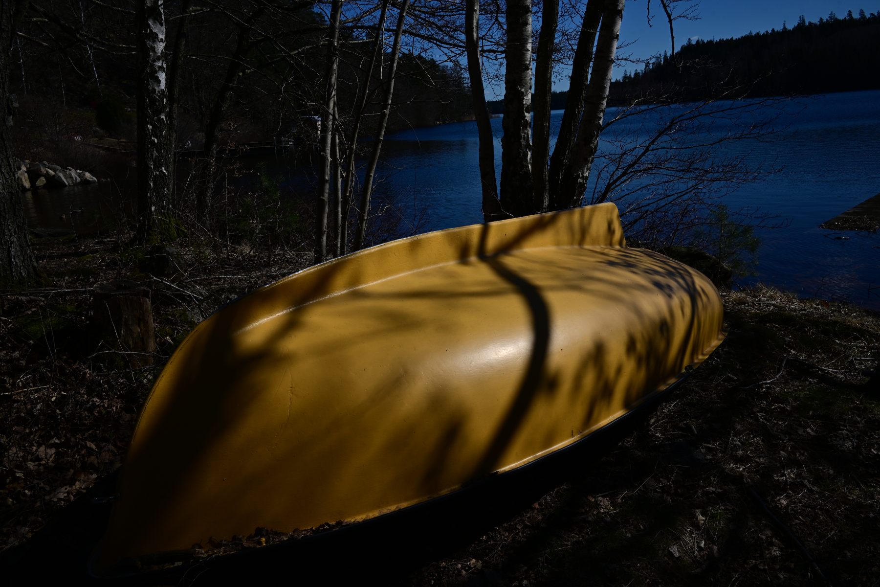 An overturned yellow canoe by the shore.